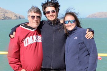 Dr. Leckie, Benjamin Keisling, and post-doc smiling at camera on deck of ship overlooking ocean