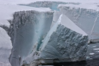 Iceverg calving off of cliff, into water, in the Antarctic. Photo by Ian Phillips