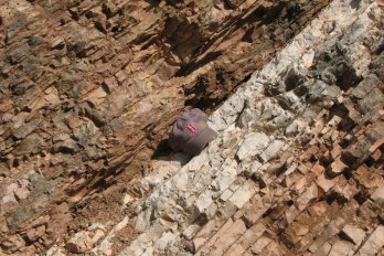  Rocks near Gubbio, Italy, change in color and texture at the line indicating the Cretaceous-Paleogene extinction event that wiped out the dinosaurs 66 million years ago. A baseball hat shows scale. Photo by Dr.'s Robert DeConto and Mark Leckie, UMass Geosciences, CC BY-ND 