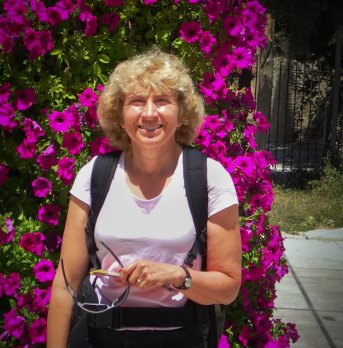 Dr. Sheila Seaman in front of purple bougnavilla bush, smiling at camera.