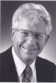 Black and white portrait of Professor George McGill, smiling at camera